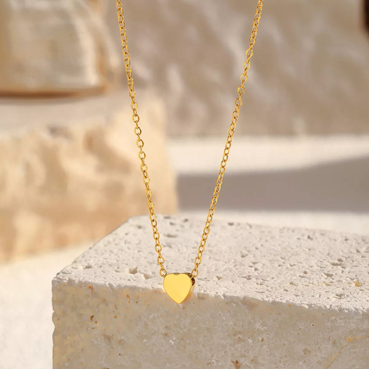 Golden Heart Pendant Necklace in gold, shown on a stone display