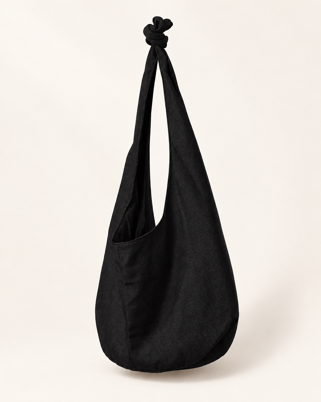 Everyday Canvas Crossbody Bag in Black, knotted fabric strap and soft rounded body on an ivory background